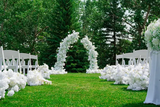 Outdoor wedding aisle with white floral arches