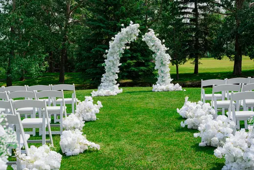 Outdoor wedding ceremony with white floral arch