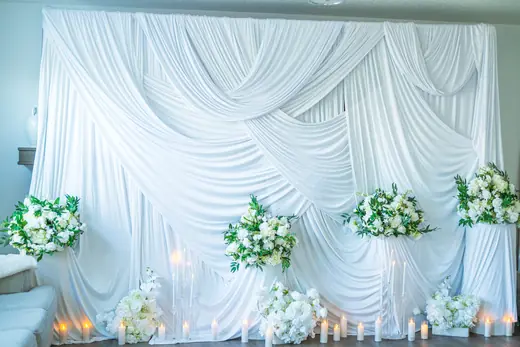 White draped event stage with floral accents